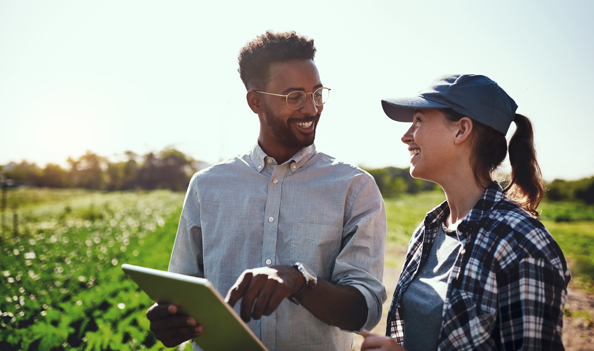 Cropped shot of two young farmers looking at a tablet while working on their farm